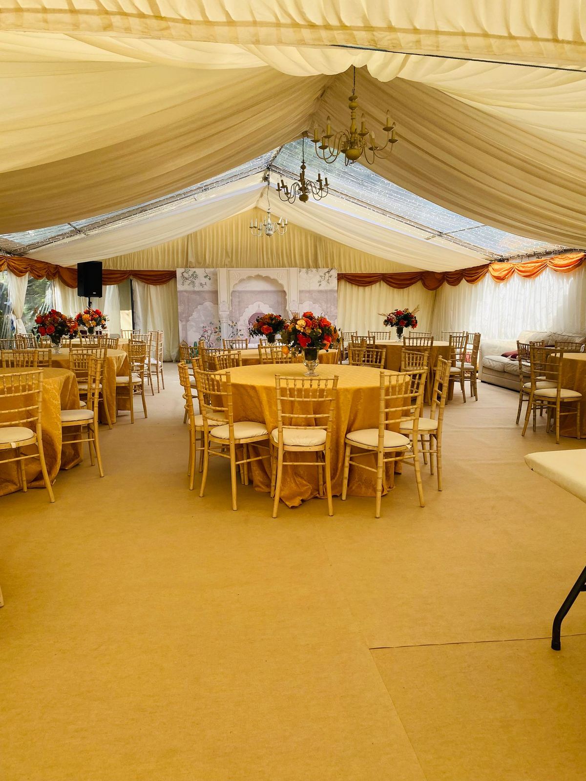 Gold-themed marquee reception with floral centrepieces