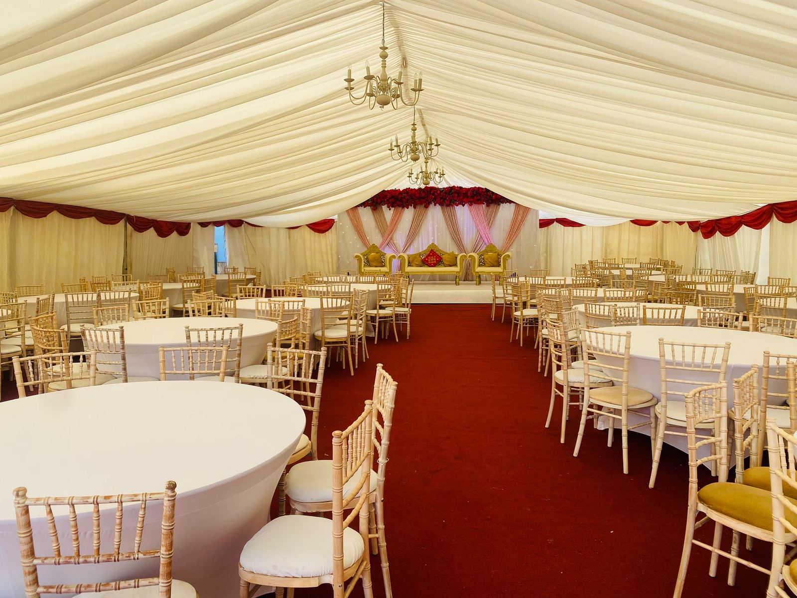 Marquee reception set with red and gold drapery