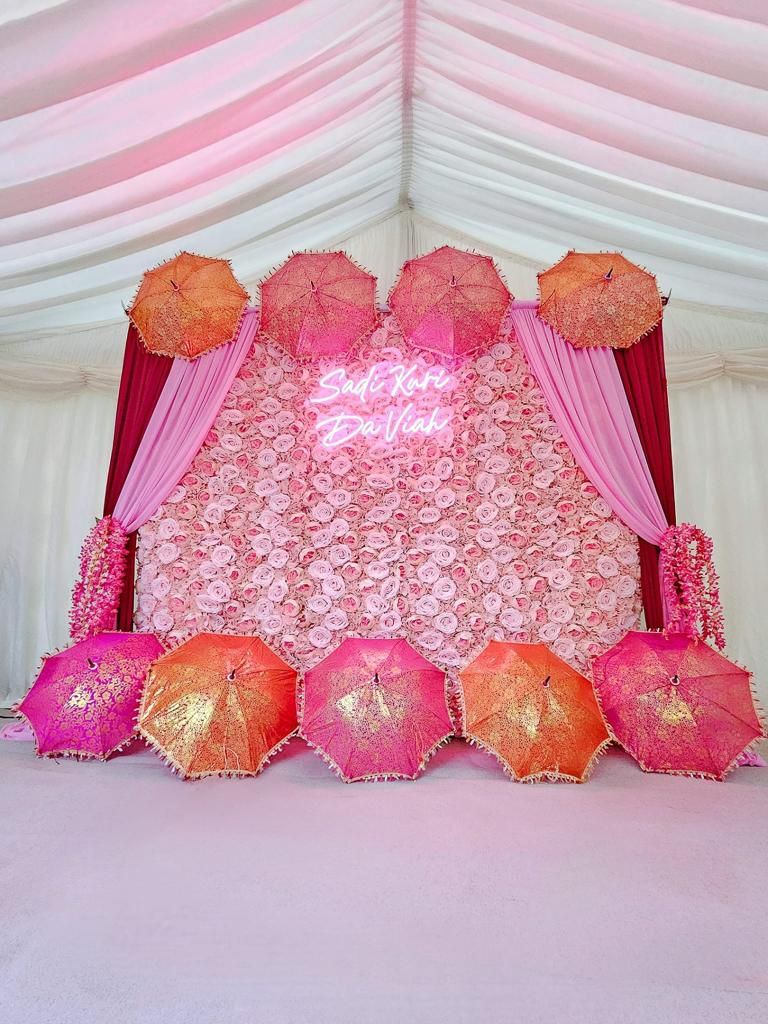 Pink and orange umbrella flower wall backdrop with neon sign
